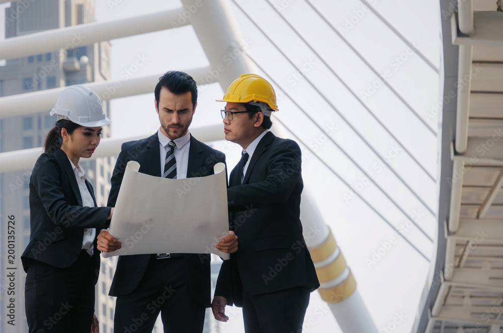 group of business or engineer woman and man with safety helmet and blueprint planning at the building and checking their work in modern city, planning start up new project, successful concept group of business or engineer woman and man with safety helmet and blueprint planning at the building and checking their work in modern city, planning start up new project, successful concept