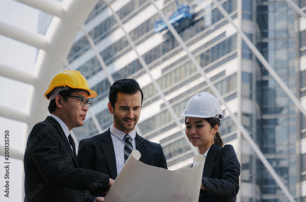 group of business or engineer woman and man with safety helmet and blueprint planning at the building and checking their work in modern city, planning start up new project, successful concept group of business or engineer woman and man with safety helmet and blueprint planning at the building and checking their work in modern city, planning start up new project, successful concept