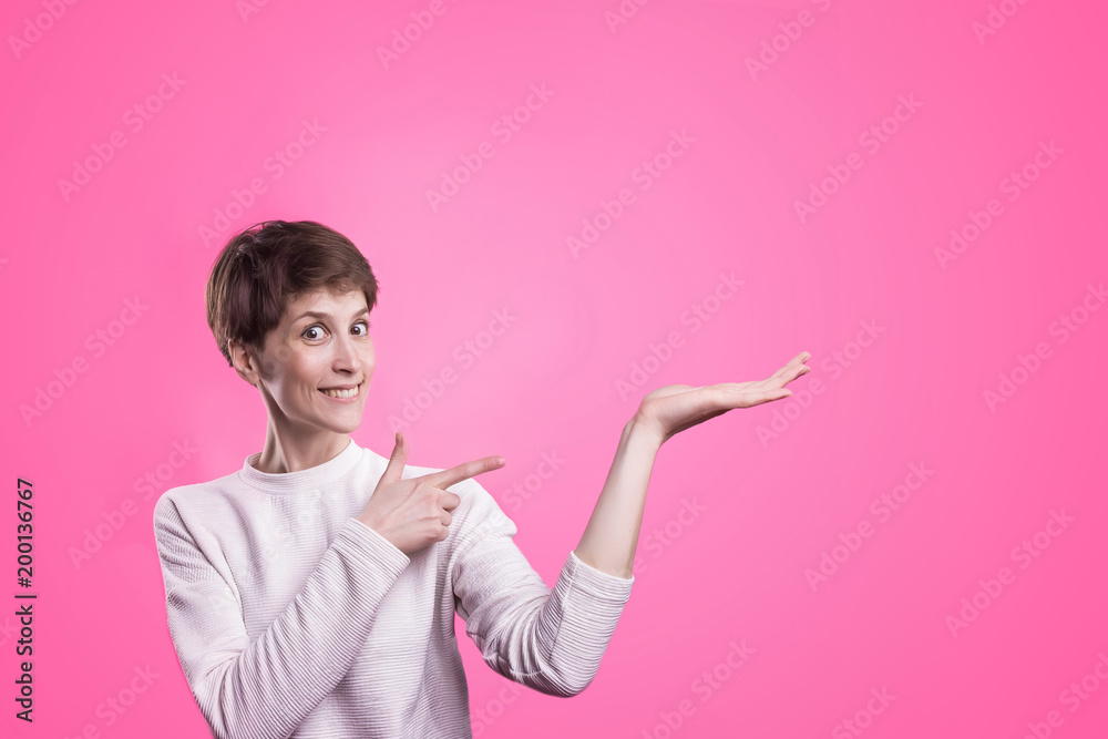 Excited girl pointing showing at pink background with copy space. Young beautiful happy smiling and laughing woman Excited girl pointing showing at pink background with copy space. Young beautiful happy smiling and laughing woman