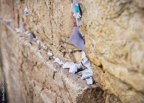 Selective focus on notes to God in the cracks between the bricks of the Western Wall, also known as Kotel, in the old city of Jerusalem, Israel