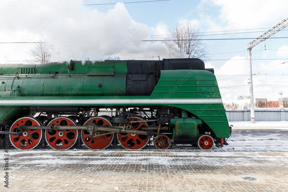 Naklejka premium old black steam locomotive in Russia in the winter on the background of the Moscow railway station