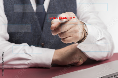 Business man sitting at desy pressing a virtual button saying data security.