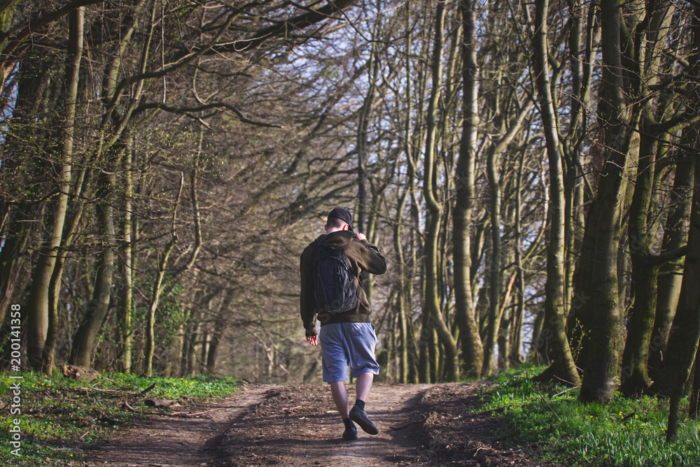 Traveler is walking on footpath through forest alone Traveler is walking on footpath through forest alone