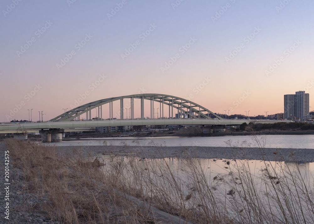 Naklejka premium Koryto rzeki i most łukowy o zmierzchu