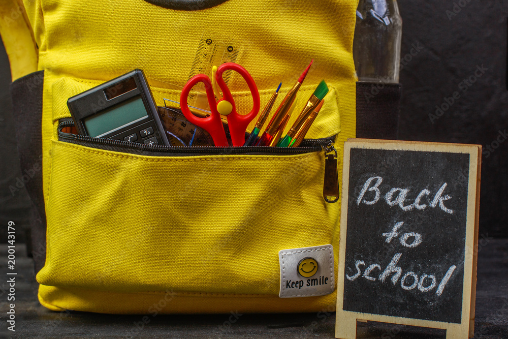 Obraz premium Yellow school backpack with accessories on black background