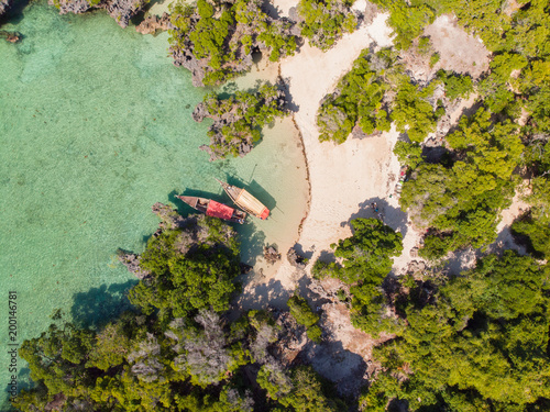 Aerial view of a beautiful tropical island and beach, small fisherman boat on clear blue reef water along Africa, Tanzania, Zanzibar. Indian Ocea