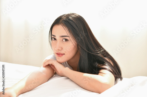Lifestyle Concept. Cute Asian girl in night dress. Beautiful asian woman is relaxing in a white bedroom. Asian girls are playing in the bedroom happily.