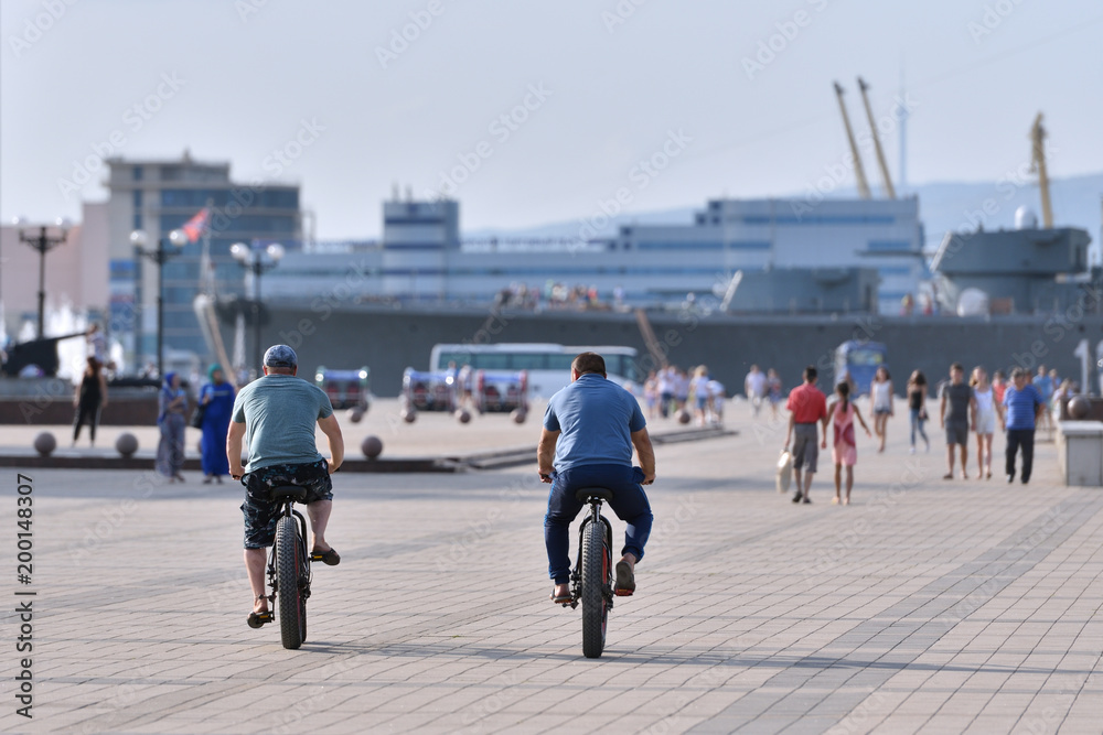 Obraz premium Two men ride bicycles with large wheels and plump tires, the view from the back
