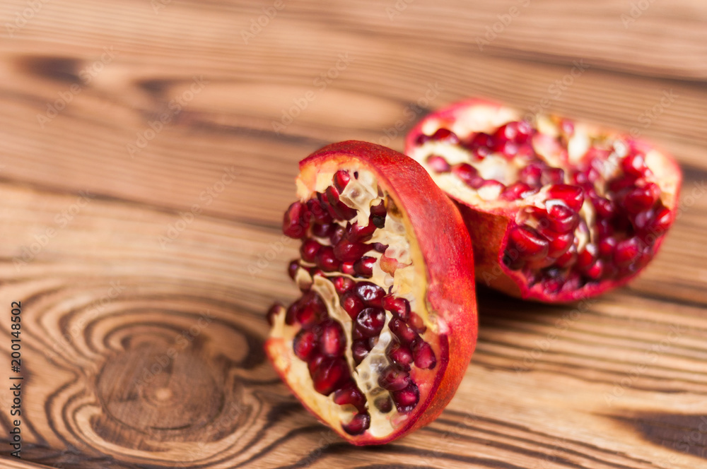 Two half red fresh ripe pomegranate with seeds on old brown weathered wooden planks Two half red fresh ripe pomegranate with seeds on old brown weathered wooden planks