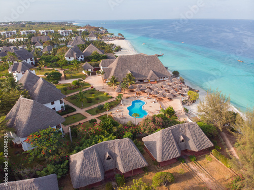 Aerial view of a beautiful tropical island and beach, small fisherman boat on clear blue reef water along Africa, Tanzania, Zanzibar. Indian Ocean