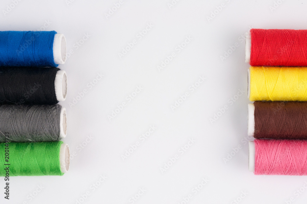 Two rows of bobbins of new colorful threads on white background. Top view Two rows of bobbins of new colorful threads on white background. Top view