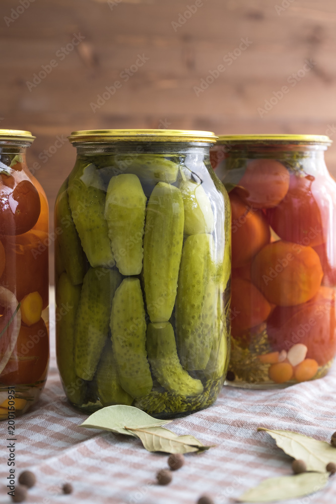 Pickled cucumbers and tomatoes in a glass jar on the table. Pickled cucumbers and tomatoes in a glass jar on the table.
