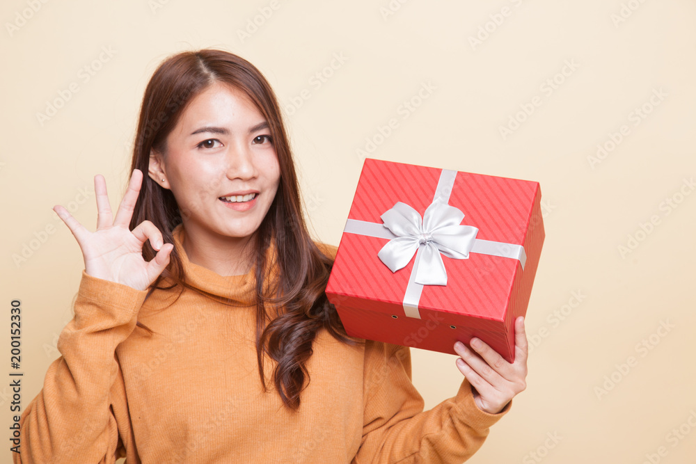 Young Asian woman show OK with a gift box. Young Asian woman show OK with a gift box.