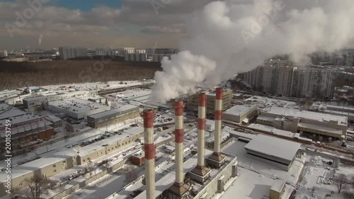 Aerial fly over view near city district power plant smoke steam pipes in sunny winter day