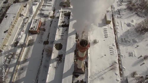 Aerial fly over view near city district power plant smoke steam pipes in sunny winter day