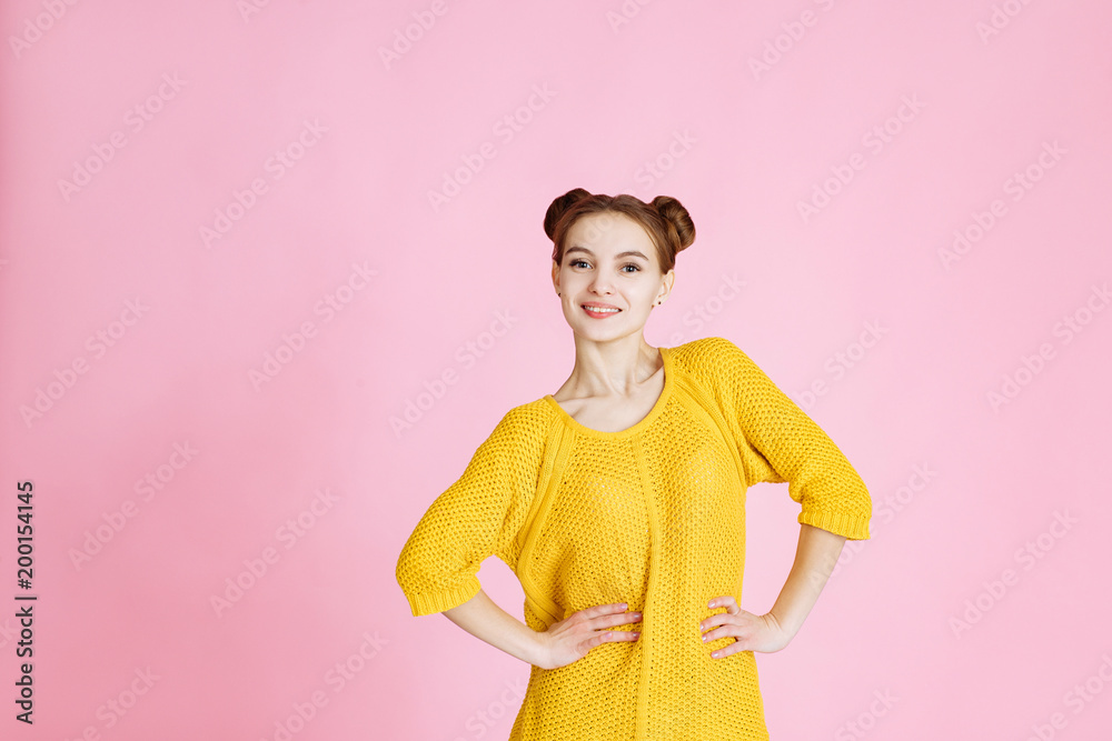 portrait of young attractive girl on pink background in Studio. Blonde in a yellow sweater with hair gathered in her hair, looking at the camera and smiling. portrait of young attractive girl on pink background in Studio. Blonde in a yellow sweater with hair gathered in her hair, looking at the camera and smiling.