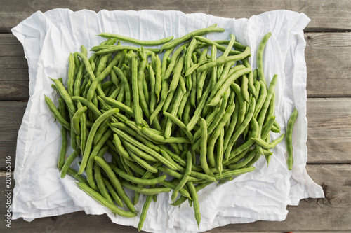Close-up of green beans on white cloth against wooden background