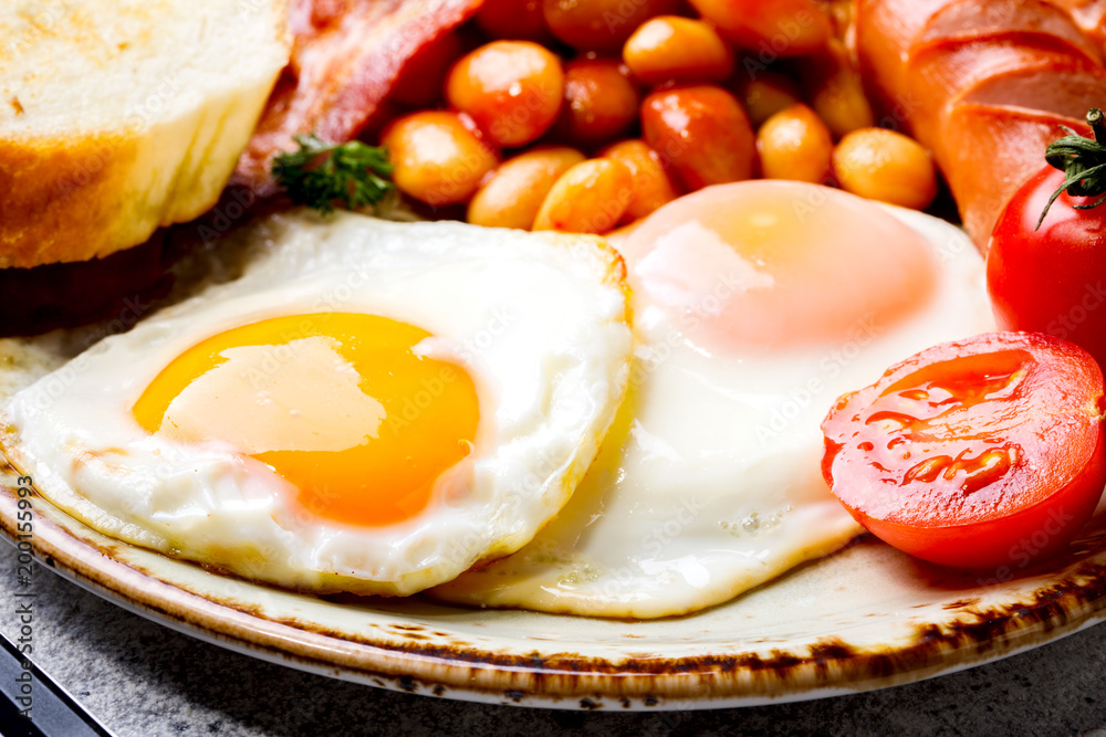 Traditional English Breakfast Food on stone Eggs ,Sausages, Bacon, Beans,Toasts Traditional English Breakfast Food on stone Eggs ,Sausages, Bacon, Beans,Toasts