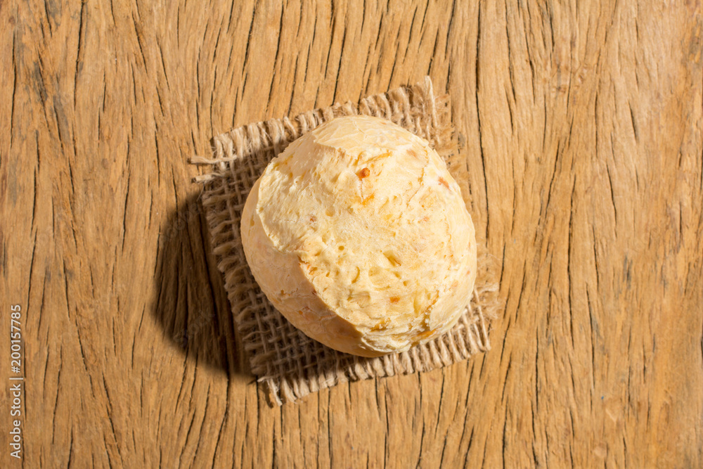 Pao de Queijo is a cheese bread ball from Brazil. Also known as Chipa, Pandebono and Pan de Yuca. One snack on rustic wood table, top view.
