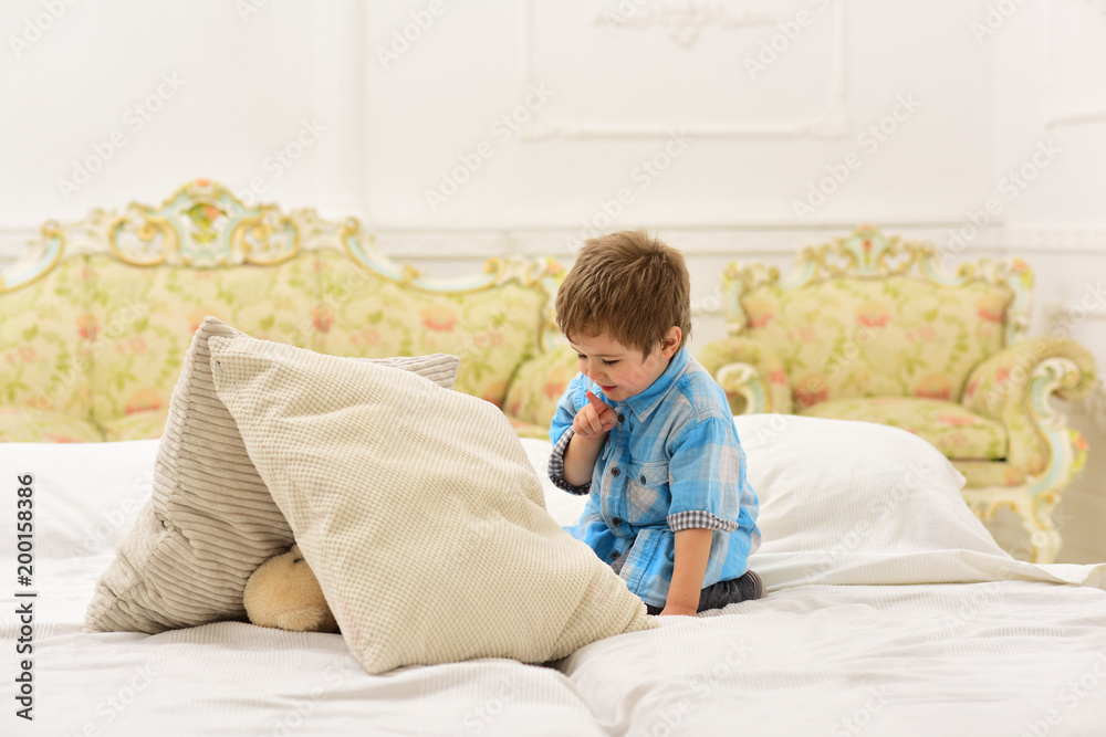 Boy happy, made house for favourite toy. Kid put plush bear under pillows, luxury interior background. Child in bedroom with silence gesture. Time to sleep concept. Little cute toddler with toy. Boy happy, made house for favourite toy. Kid put plush bear under pillows, luxury interior background. Child in bedroom with silence gesture. Time to sleep concept. Little cute toddler with toy.