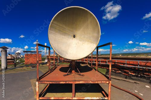 Rusty telecommunication tower with old satellite system consist of old satellite dish antenna is  located on the roof and blue sky as background. Outdoor equipment of retro satellite system  photo