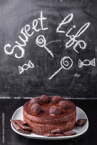 Chocolate cake on a white porcelain dish on the background of a slate with the inscription Sweet life