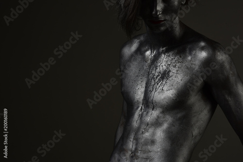 Man with nude torso covered with shimmering silver paint,