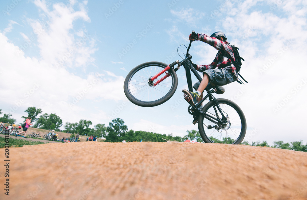 A young man makes tricks on a mountain bike. A cyclist jumps on a bike.