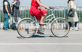 Lady on a bike. The girl in the red dress riding a bike around the city. A bicycle ride in the city on the background of people