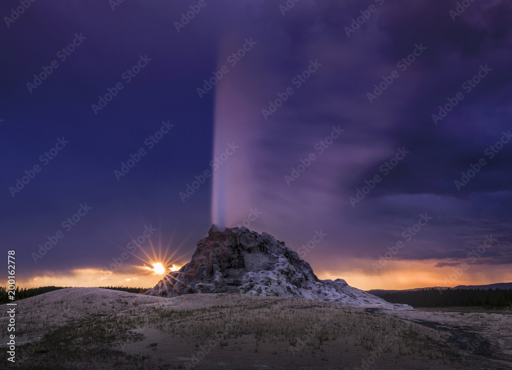 White Dome Geyser erupting at sunset in the Lower Geyser Basin in Yellowstone National Park, Wyoming, USA