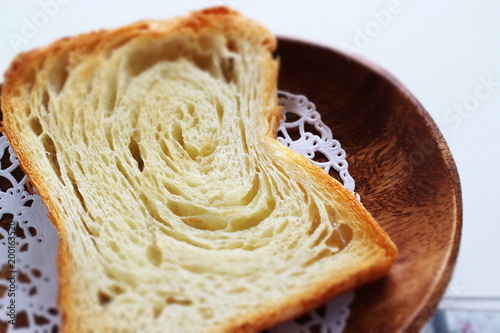 Pastry style sliced bread on wooden plate