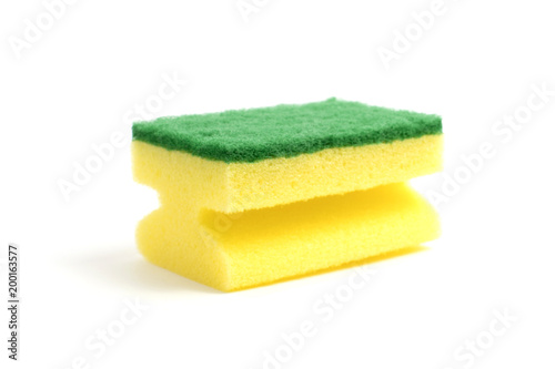 Photo of a dish sponge that consists of yellow foam and green abrasive on a white background
