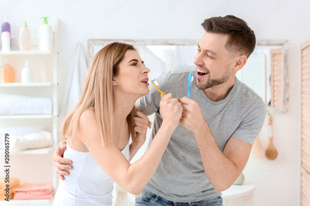 Young couple brushing teeth together in bathroom Young couple brushing teeth together in bathroom