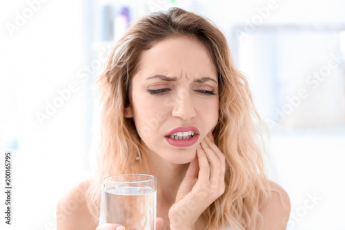 Young woman suffering from toothache indoors