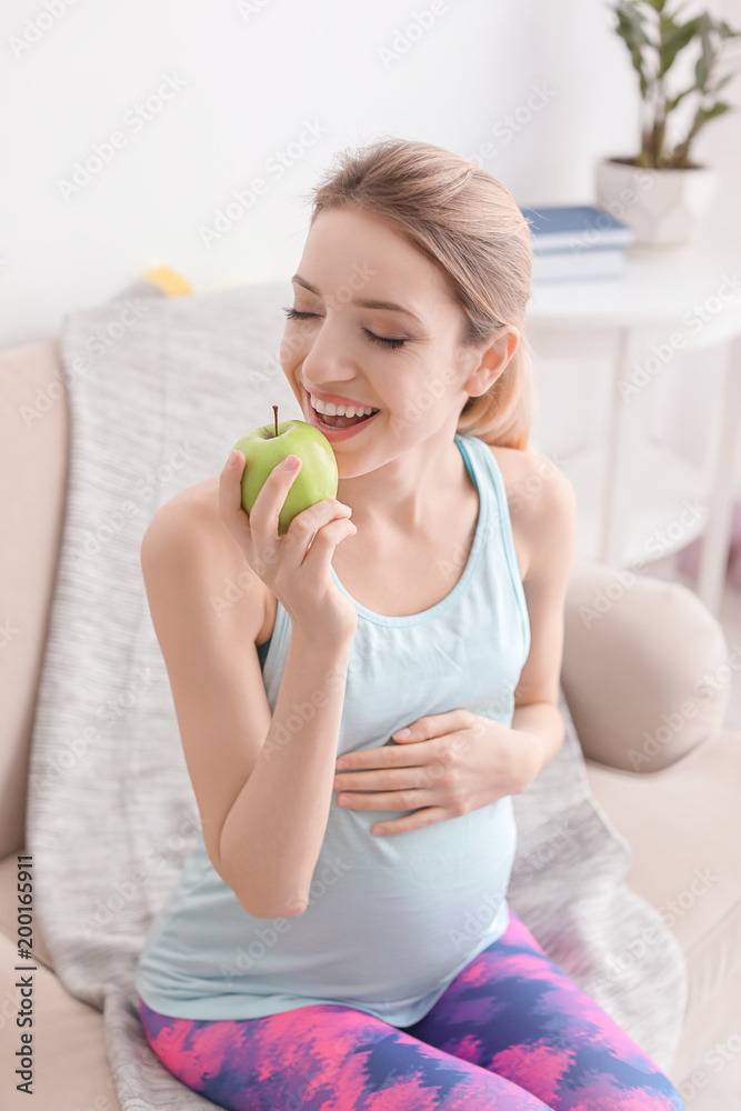 Young pregnant woman eating apple at home Young pregnant woman eating apple at home