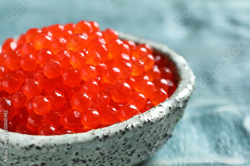 Ceramic bowl with delicious red caviar on table, closeup