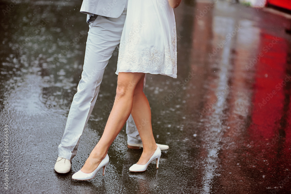 Wedding couple dancing in the rain. Close up dynamic shot in motion. Reflections on the water. Love story