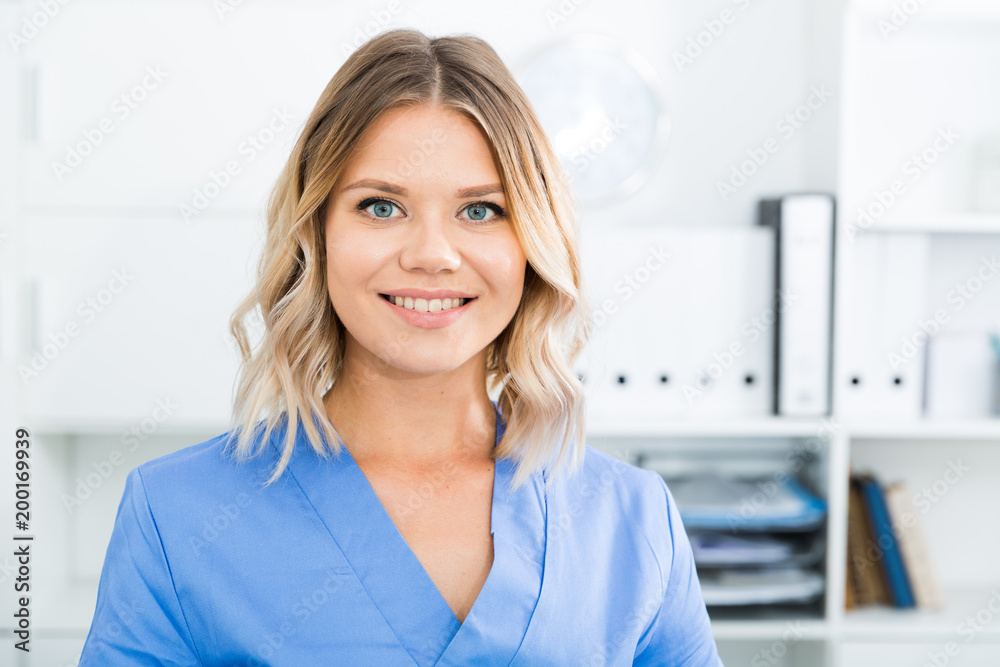Kindly woman in doctor's uniform greets visitors at modern office