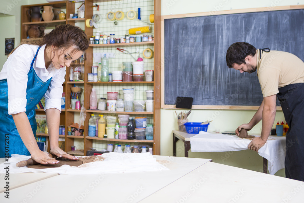 Pottering and Clay Making Process Concepts. Two Professional Clay Makers During a Process of Clay Preparation on Tables in Workshop. Pottering and Clay Making Process Concepts. Two Professional Clay Makers During a Process of Clay Preparation on Tables in Workshop.