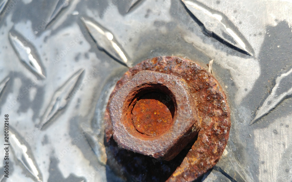 A rusted bolt screw on textured steel A rusted bolt screw on textured steel