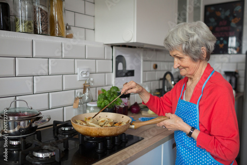Senior woman cooking food in kitchen photo