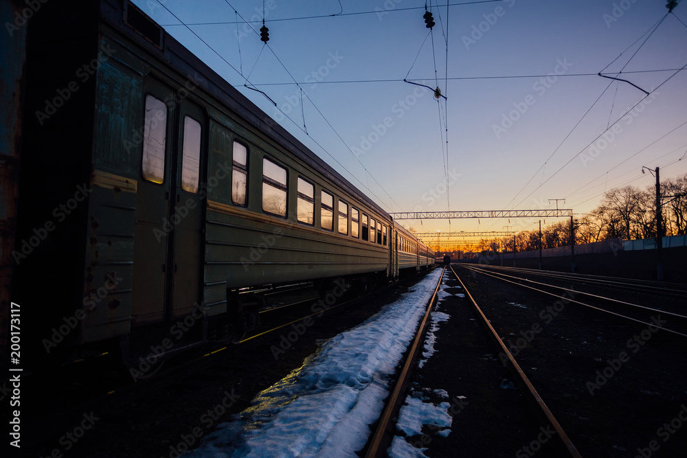 Railway with old passenger train in sunset background