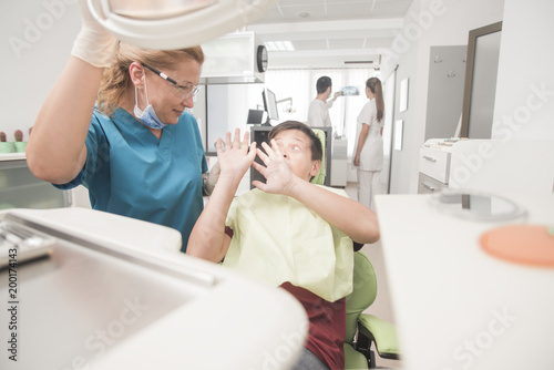 Boy with perfect teeth at the dentist doing check up with the clininc at the background - oral hygiene health care concept