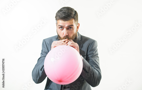 Happy birthday, preparation to party, celebration - attractive businessman with beard and mustache is blowing pink balloon. Stylish man in suit inflating balloon. Handsome bearded man hold air balloon © Svitlana