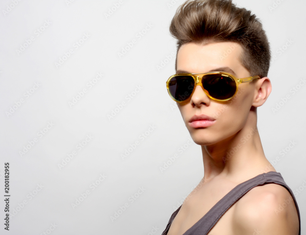 The beautiful young man in sunglasses on a white background.