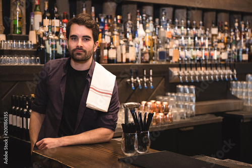 Confident bartender standing at bar counter photo