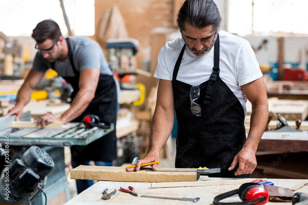 Carpenters marking on wooden plank with pencil Carpenters marking on wooden plank with pencil