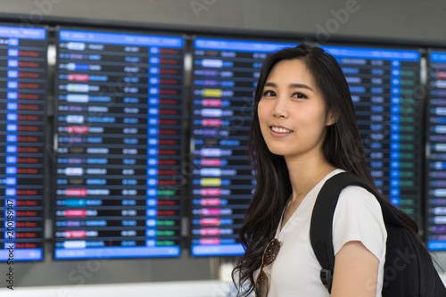 Asian traveler checking boarding in terminal or train station. Tourist on vacation.