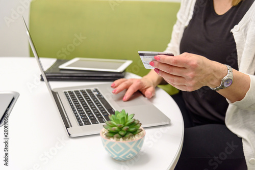 person holdng a credit card at table with laptop computer
