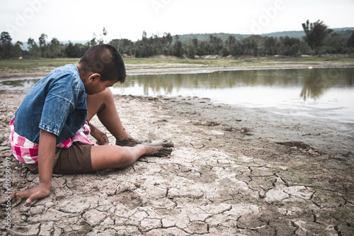 Men on ground cracked dry due to drought  food shortages and water   Concept drought and crisis environment.